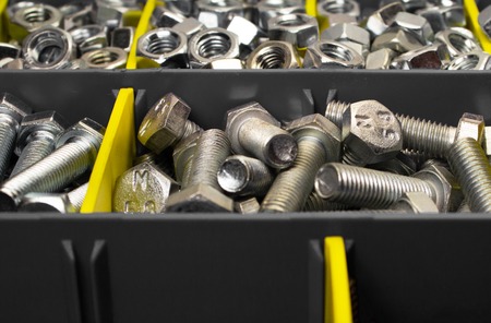new bolts and nuts in a container with gray and yellow partitions, close-upの写真素材