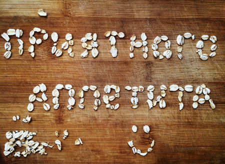 top view of inscription bon appetit in Russian flakes of rolled oats on a wooden kitchen boardの写真素材