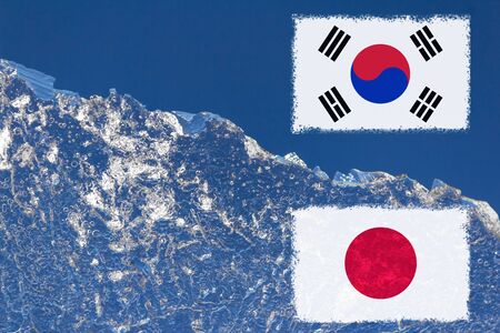the flag of Japan and South Korea are painted at opposite end of piece of ice in the form of an arctic iceberg against blue sky.の写真素材