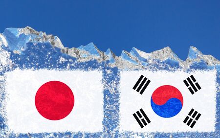 the flag of Japan and South Korea are painted at opposite end of piece of ice in the form of an arctic iceberg against blue sky.の写真素材