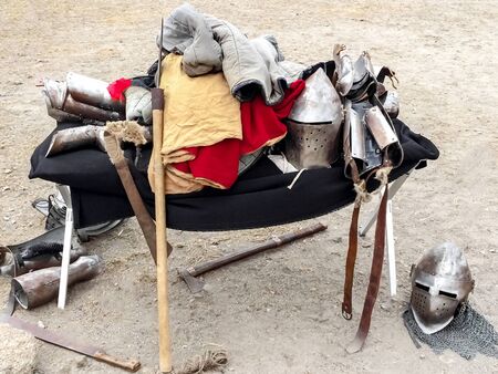the clothes, armor and weapons of the medieval knight lie mountain on felt in the open air. Protective antique helmet, chainmail, battle ax, metal battens, festival reconstructionの写真素材