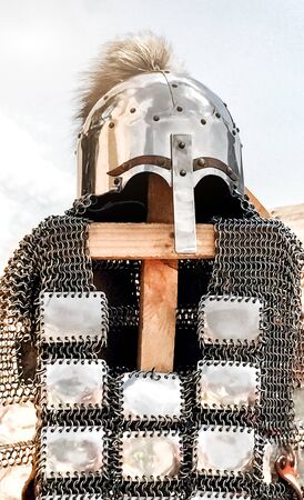 antique warrior armor, shiny metal helmet with nose protection and fur decoration, shirt with metal plates, armor thrown over wooden slats as exhibits at the festivalの写真素材