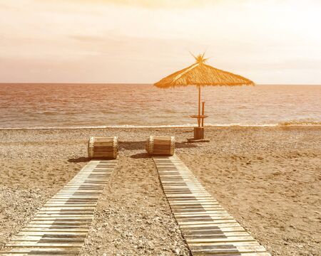 straw umbrella on a summer morning on a sandy sea beach on vacationの写真素材