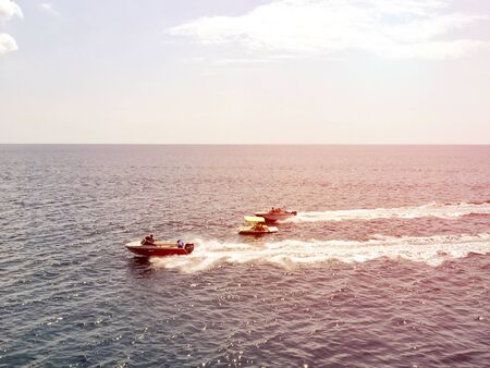 Top view on two white motorboats sail in the blue sea and leave white streaks, compete in speed at sea, racing two boats in sunriseの写真素材