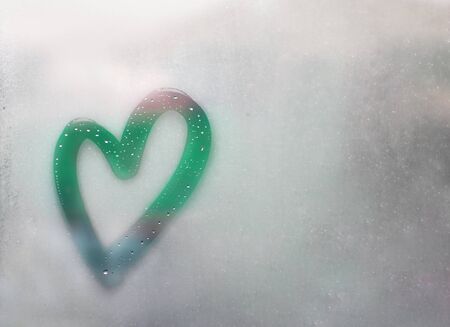 heart outline painted on sweaty glass, there are many drops on it, turquoise, mint inscription heart and love handmade on a wet autumn foggy glass. valentines day concept with copy space for textの写真素材
