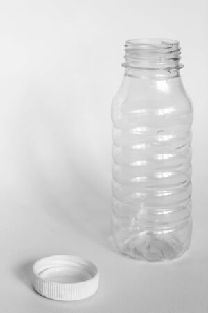 empty transparent open plastic bottle without cap, cap lies next to a white background, the concept of debris removalの写真素材