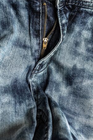 close-up zipper open on blue jeans, denim texture, zipper jeans pants half open, shabby denim fabric textureの写真素材