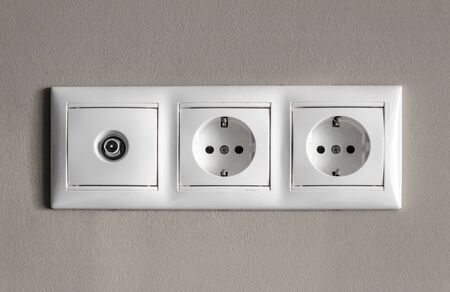 electrical outlets, set of three white empty electrical sockets and antenna socket for TV with light shadow on empty grey background, electrical point of power in house, closeup, minimalism conceptの写真素材