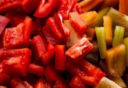 Closeup fresh sweet bell peppers of red and yellow cut into large cubes, cooking ingredients for a seasonal seasonal vegetable dishの写真素材