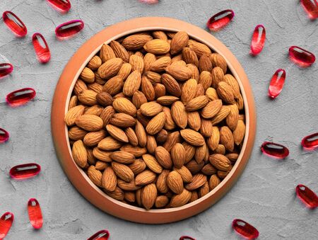 organic food and chemical medicines, biologically active food supplement, almonds and chemical red vitamins on a gray background, top view, healthy eating concept, BAAの写真素材