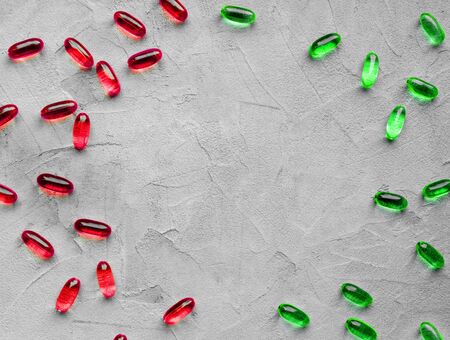 multicolored red and green gelatin transparent capsules with oily drug on gray background with copy space. The concept of pharmacology, homeopathyの写真素材
