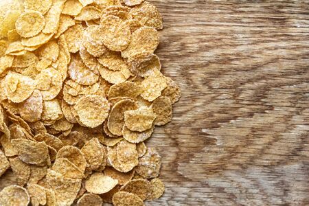 Wholemeal Cornflakes close-up on wooden background with copy space, useful breakfast whole grain corn flakes, source of dietary fiber and a prebioticの写真素材
