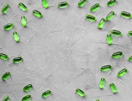 green soft gelatin transparent capsules laid out on a gray concrete background with copy space . The concept of pharmacology, homeopathy and medicine,peppermint candies, medicinal herbsの写真素材