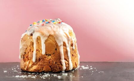 rustic cakes with icing and colored confetti close-up standing on a black surface with icing crumbs on a pink background. Morning baking, easter card with copy spaceの写真素材