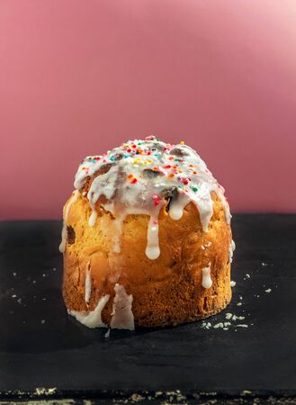 rustic cakes with icing and colored confetti close-up standing on a black surface with icing crumbs on a pink background. Morning bakingの写真素材