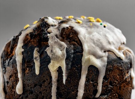 rustic brown biscuit cake with icing on a gray background. Glaze flows down white smudges with colorful powders and candy, confetti close-up. Symbol of Russian Easter. Easter cardの写真素材