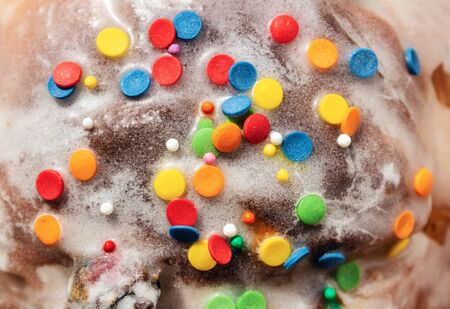 Sugar colored confetti lies on a white icing rustic cake, texture of sugar icing on a cupcake surface close-up, green, red, blue, orange and white candy flat lay, Happy birthday conceptの写真素材