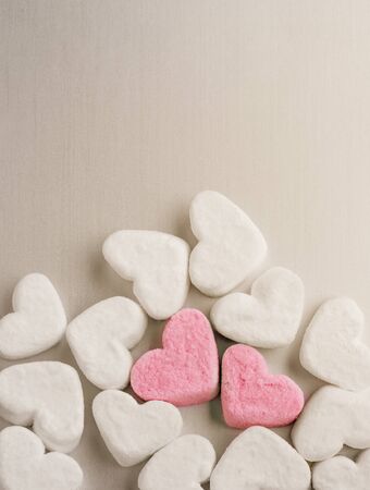 two pink marshmallow hearts lies among white sugar marshmallows in the shape of hearts evenly on gray aluminum background with copyspaceの写真素材