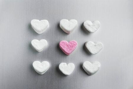 pink marshmallow heart lies among white sugar marshmallows square shaped on a gray aluminum background, valentines day conceptの写真素材