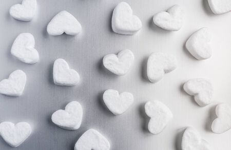 white sugar heart-shaped marshmallows evenly laid out on a gray aluminum backgroundの写真素材