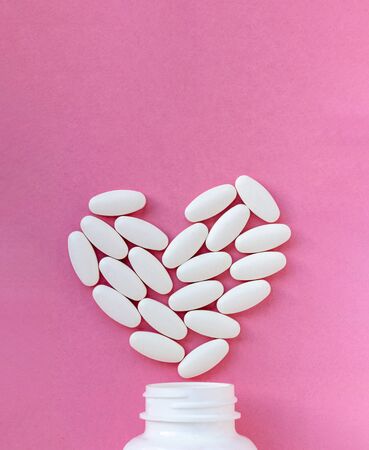 Heart made of pills over the neck of a bottle on pink background. Copy space for text. Valentine's Day Pillsの写真素材