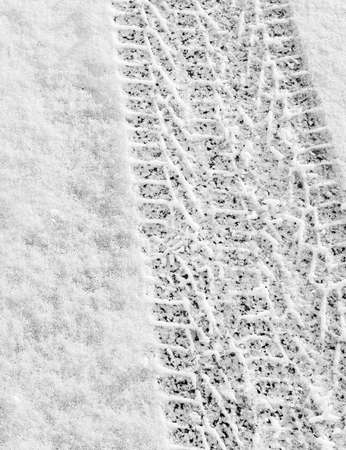 closeup of a car tire trace on thin white snow in winter recede into the distance, vertical frame, ribbed tread, winter concept with copyspaceの写真素材