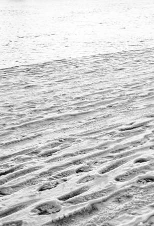many footprints from shoes on white snow vertical frame on the background of water in the riverの写真素材