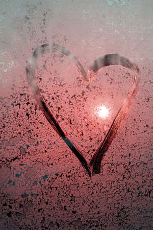 Pink Heart drawn by a finger on misted frosty glass with sun glare, a symbol of happy love, strawberry heart, a message of love, Valentine's Dayの写真素材