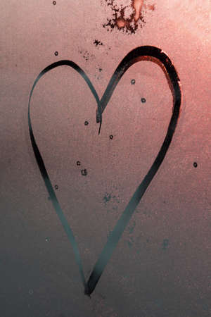 contour of Heart drawn with a finger on pink misted frosty glass with sun glare, symbol of happy love, strawberry heart, message of love, Valentine's Dayの写真素材
