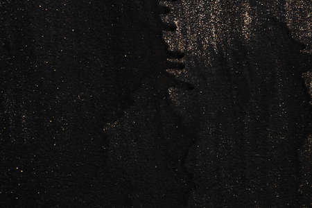 The metal texture of the background painted in black paint with smudges, scratches and splashes of gold sparkles, copy spaceの写真素材