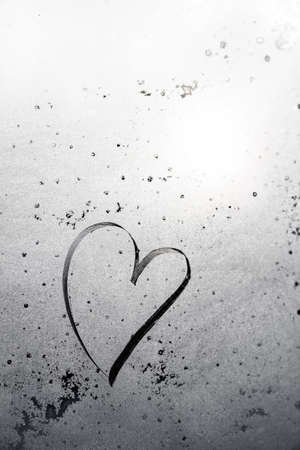 heart symbol drawn on misted glass with the sun, black and white photography. copy space for an inscription. vertical frameの写真素材