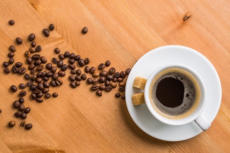 Coffee cup, sugar and coffee beans on wooden background. Top view.