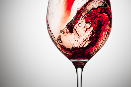 Stream of wine being pouring into a glass. Closeup splash of wine.の写真素材