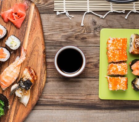 Set of sushi rolls and sashimi with soy sauce on wooden background, top viewの写真素材