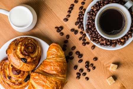 Coffee cup with cinnabon and croissant on wooden background. Top view.の写真素材