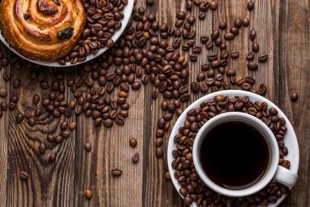 Coffee cup with coffee bean and cinnabons on wooden background. Breakfast background.の写真素材