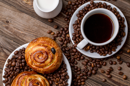 Coffee cup with milk jug and cinnabons on wooden background. Top view.の写真素材