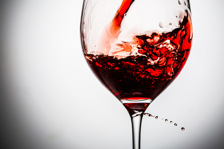 Stream of wine being pouring into a glass. Closeup splash of wine.の写真素材