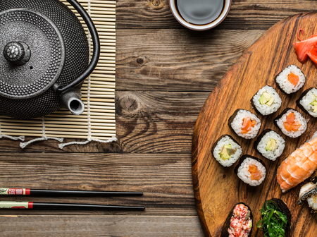 Japanese seafood sushi, rolls and teapot served on wooden surfaceの写真素材