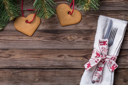 Christmas table place setting with fork and knife,decorated ribbon and bow, christmas pine branches and cookies. Christmas holidays background.の写真素材