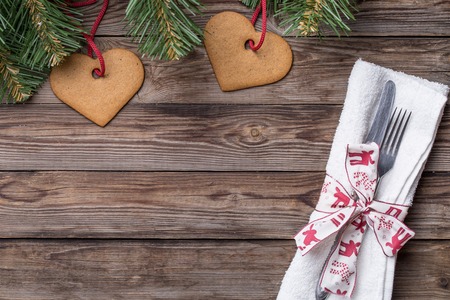 Christmas table place setting with fork and knife,decorated ribbon and bow, christmas pine branches and cookies. Christmas holidays background.の写真素材