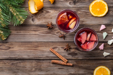 Two glasses of hot mulled wine with oranges, apples and spices. Flat lay christmas background.の写真素材