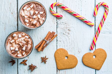 Christmas decor on wooden background with cookies in form heart, cane and two glasses of cocoa. Christmas backgrounds. View from aboveの写真素材