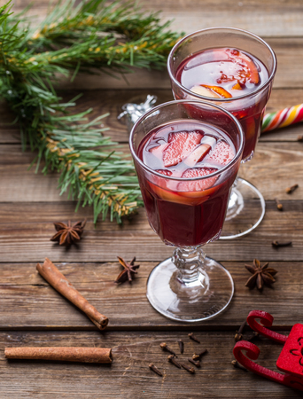 Two glasses of hot mulled wine with oranges, apples and spices. Christmas background.の写真素材