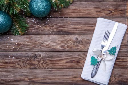 Christmas table place setting with fork and knife, decorated ribbon and bow with fir-tree toys, white napkin and christmas pine branches with christmas balls. Christmas holidays background.の写真素材