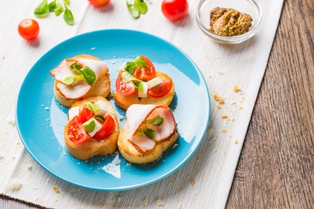 Traditional Italian antipasti bruschetta with tomato, cheese and bacon.の写真素材