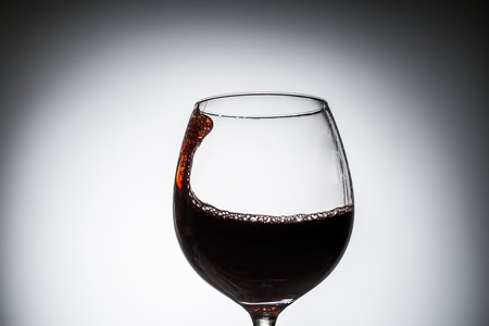 Stream of wine being pouring into a glass. Closeup splash of wine.