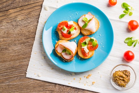 Traditional Italian antipasti bruschetta with tomato, cheese and bacon. Flat lay.の写真素材