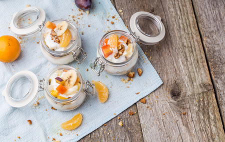 Healthy breakfast overnight oats with fresh fruit in a glass jar on wooden backgroundの写真素材