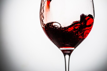 Stream of wine being pouring into a glass. Closeup splash of wine.の写真素材